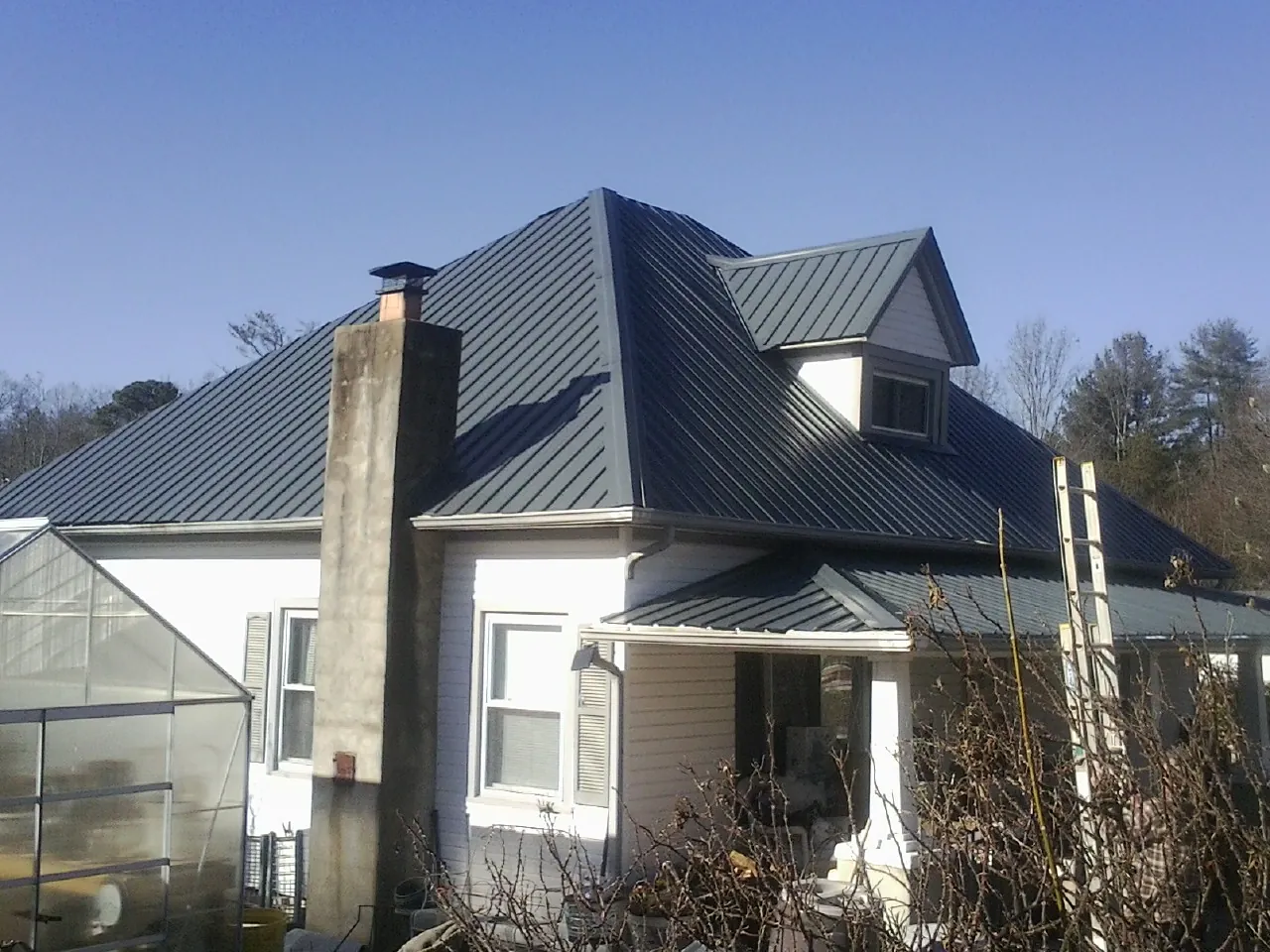 Dark blue standing seam metal roof on a white farmhouse with dormer — Slate & Tile Roof Repair by Roofing Brothers in Roebuck