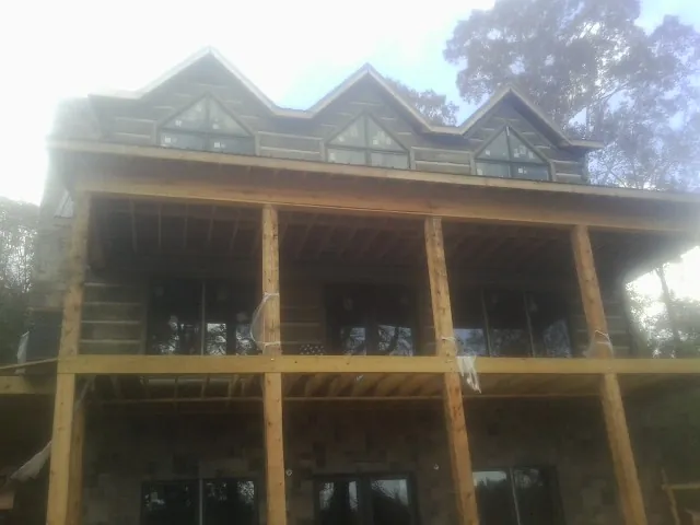 Dormers and porch framing on a large log home under construction — Roof Coating work by our crew in Roebuck