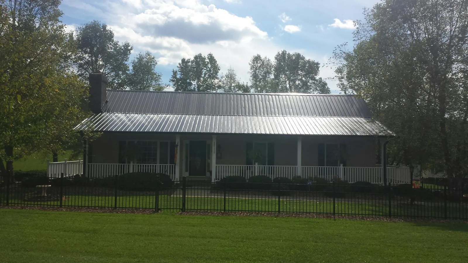 Gray metal roof on a brick ranch with a full width front porch — Gutter Guard Installation work by our crew in Roebuck
