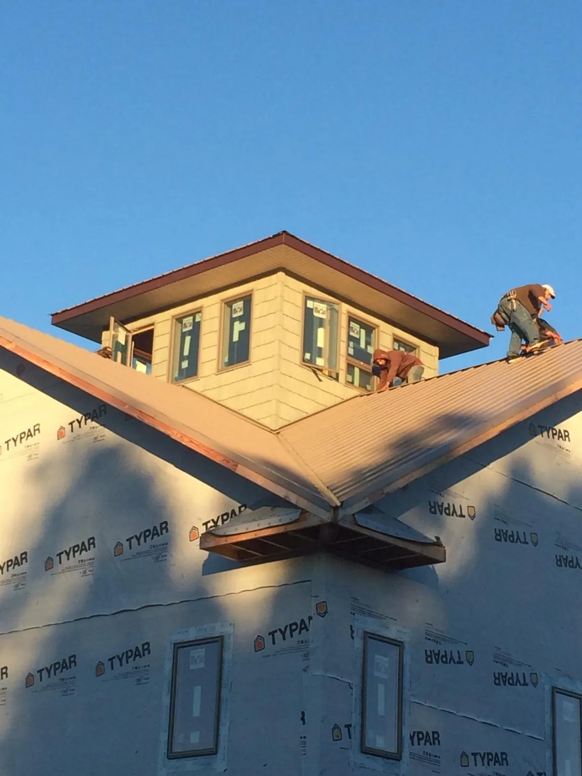 Roofers working around a rooftop cupola on a new metal roof at sunset — Roof Waterproofing in Roebuck by Roofing Brothers